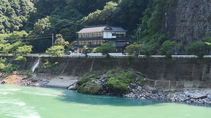 翌朝、球磨川の対岸から撮影した鶴之湯旅館の佇まい。浴室棟の屋根に太陽光パネルが載っているのがわかります。