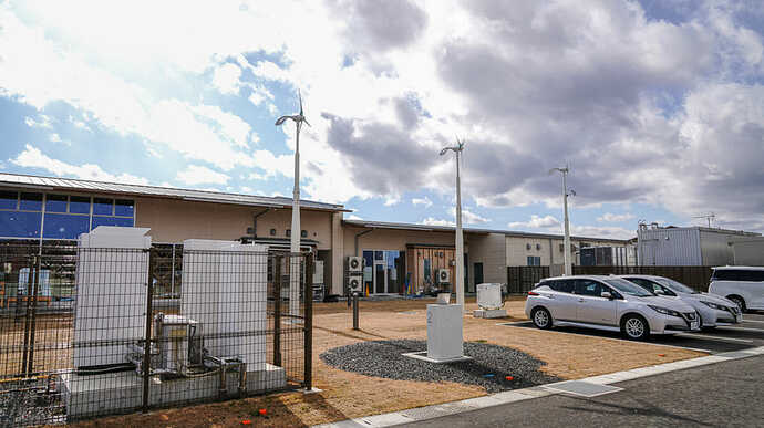 画像の左側、フェンスに囲まれた白い筐体が燃料電池発電機。太陽光パネルは後ろ側の「道の駅なみえ」建物の屋根に設置されている。