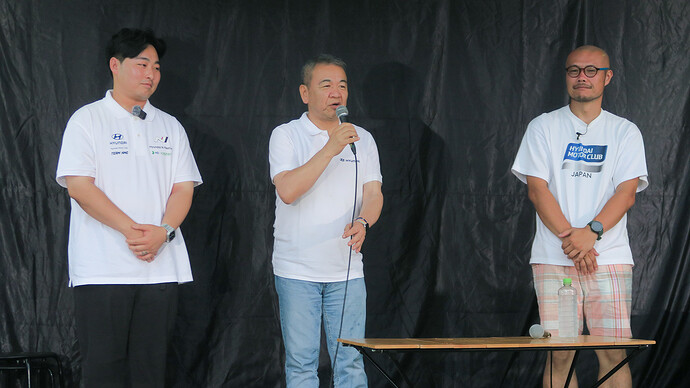 壇上で挨拶をする七五三木社長と、HMCKのキム会長（左）、HMCJの辻榮会長。