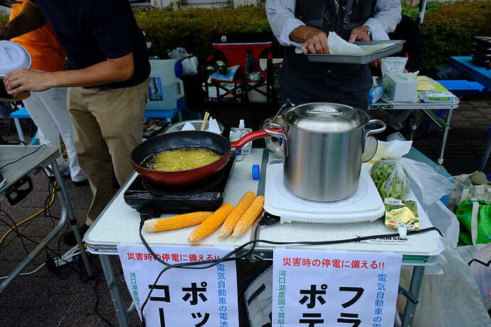 i-MiEVからMiEV Power BOXを介して電気を取り出すV2Xシステム。それでIHヒーターを駆動してフライドポテトや鶏唐揚げ、ポップコーンや茹でたての枝豆を作って見せるデモ。できたものは来場者に試食していただいたが、大好評。「停電時に心強い」と感心される方がたくさんいらっしゃった。神奈川県主催のイベント（2019年）にて。