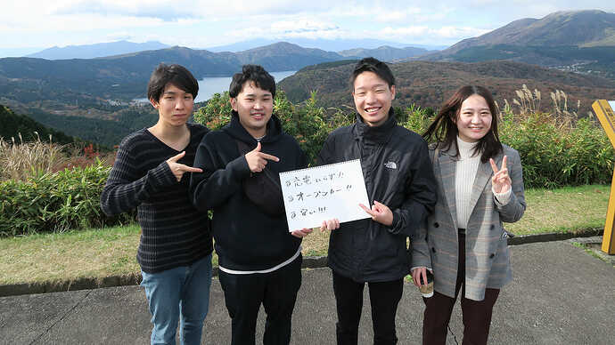 4人組の若者たち。手書きボードの意味は、後日別記事でレポートします。（寄本）