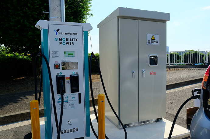 道路わきに設置されたABB製のQC本体と、付帯の変電設備。比較的コンパクトな印象。道路上に設置ということもあり、地上に落ちたケーブルにつまずいて人が転ばぬように、ケーブルがなるべく空中に位置するような工夫がなされている。ケーブルにつまずいて転んで、車線に身体が出てしまったら命にかかわります。