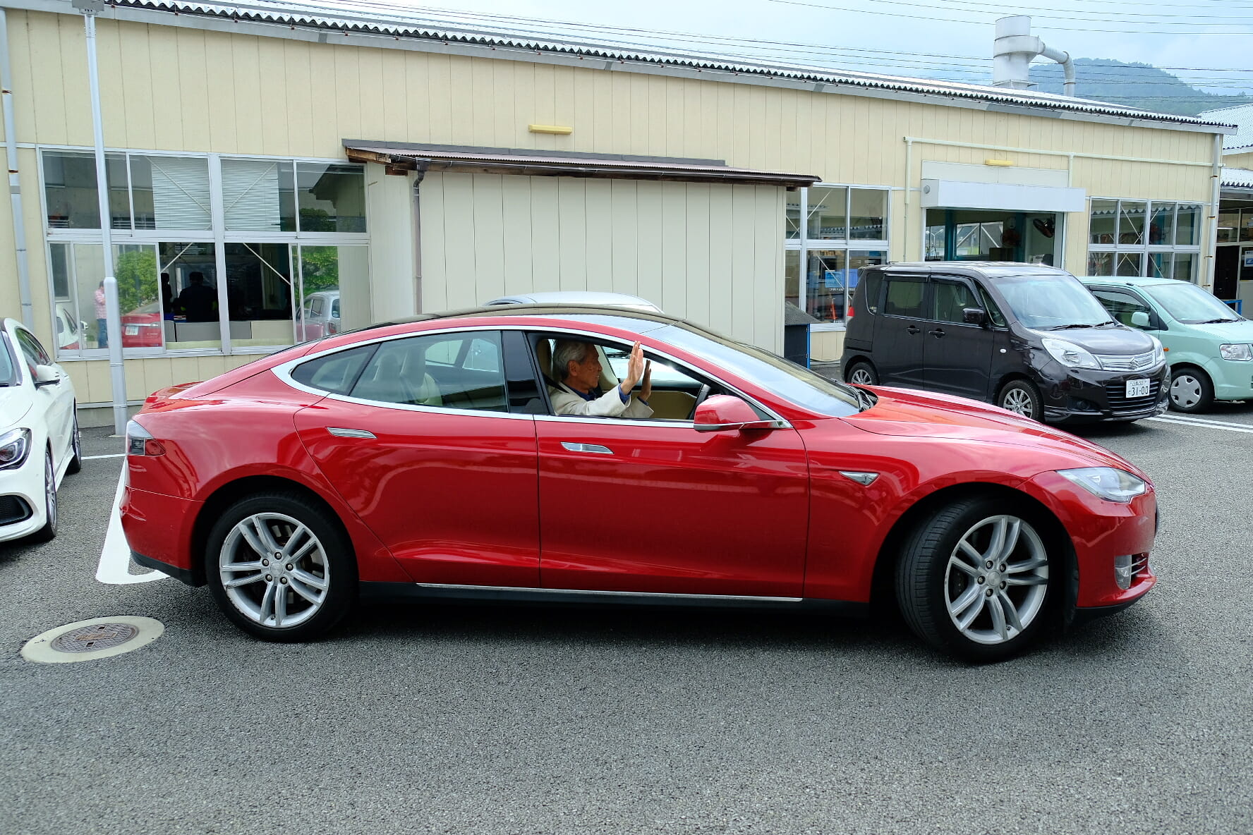 Alan demonstrating the auto-park function with his hands off the steering. Students are keenly observing how the Tesla is making fine adjustments as it moves into the parking spot.